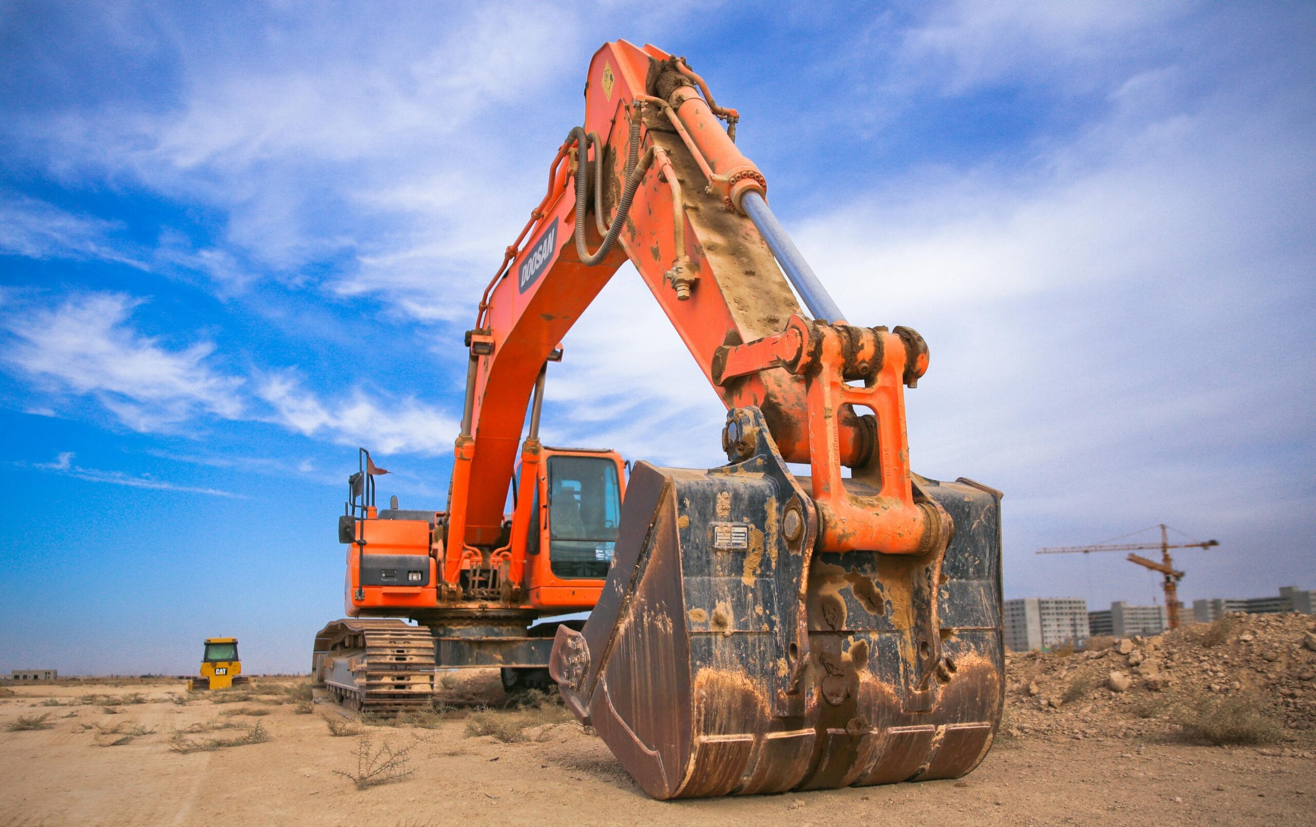 Excavator Hire in Brisbane: A Guide for Construction Professionals A large orange excavator working on a construction site under a blue sky.