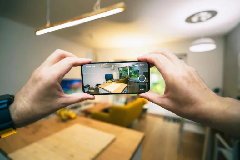 Hands capturing a modern living room interior with a smartphone.