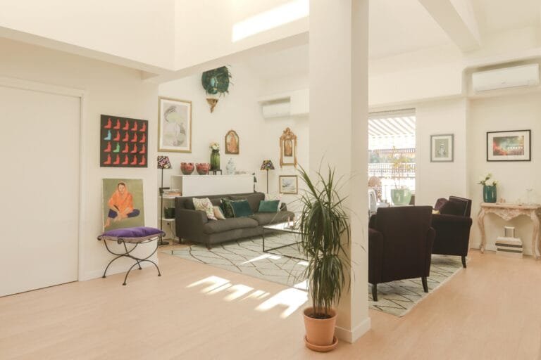 Bright modern living room with art decor, plants, and cozy furnishings.